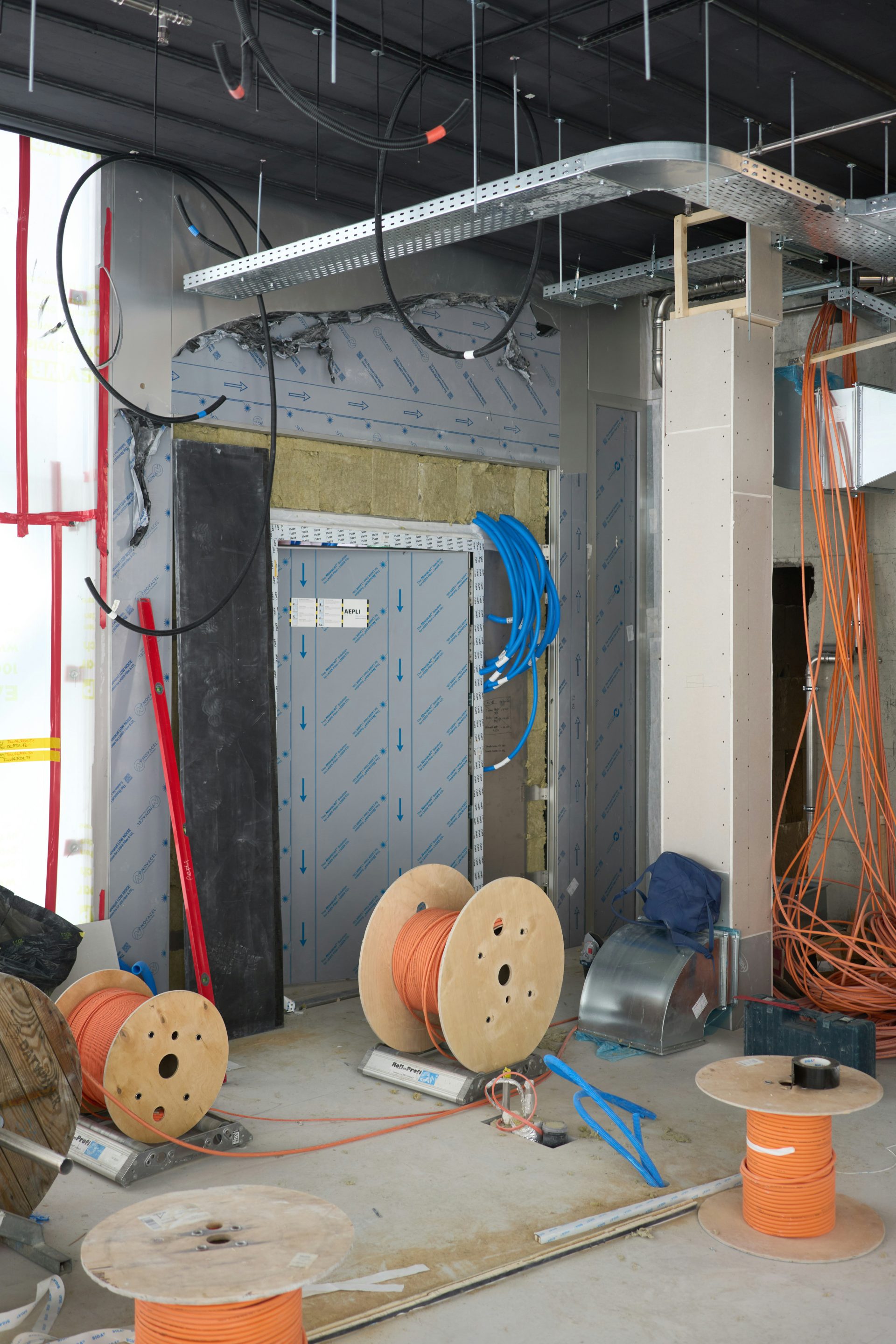 Obra en construcción con cableado eléctrico y bobinas de cable.