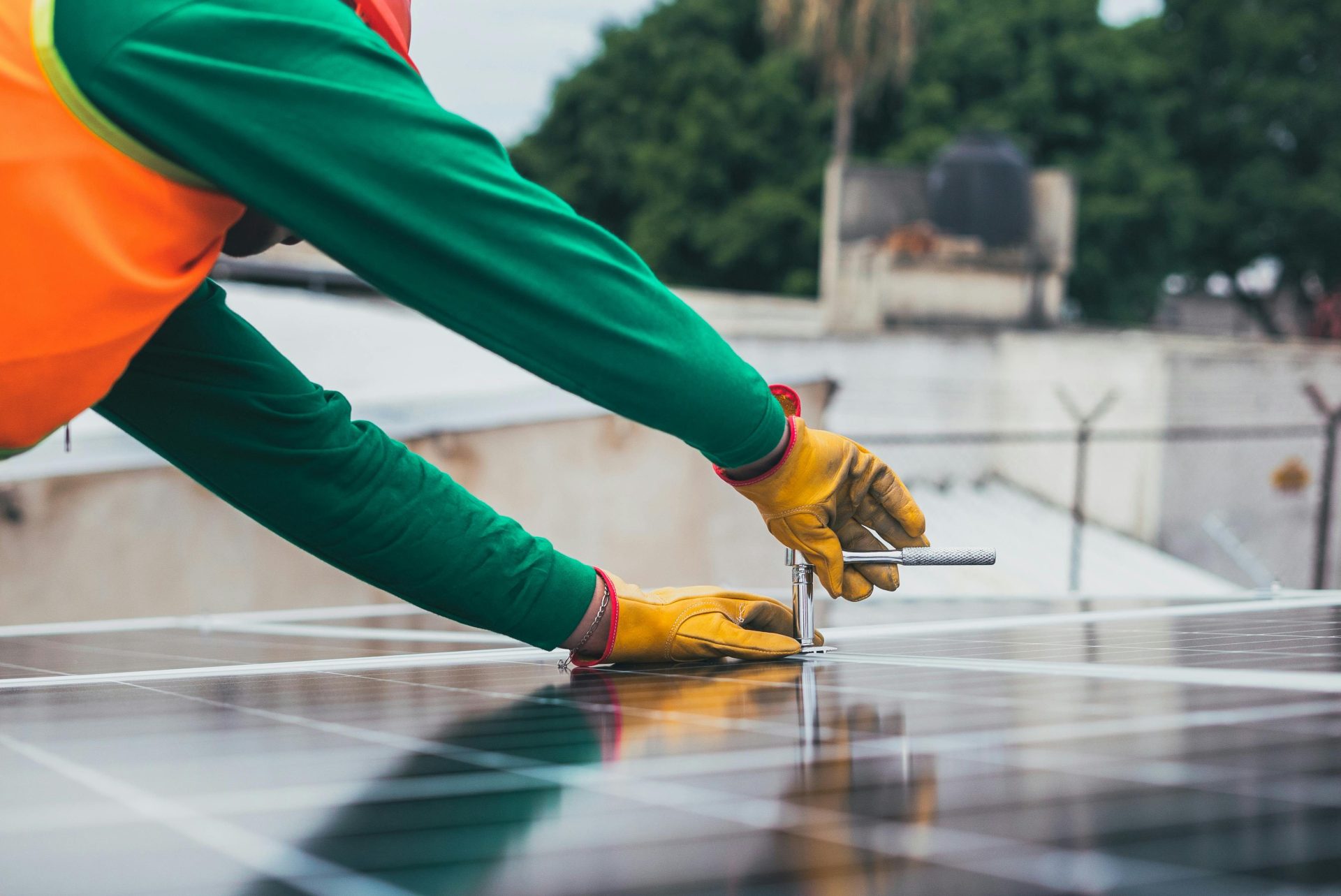 Un técnico solar trabajando en la instalación de paneles solares en un tejado, con especial atención a las herramientas y el equipo de seguridad.